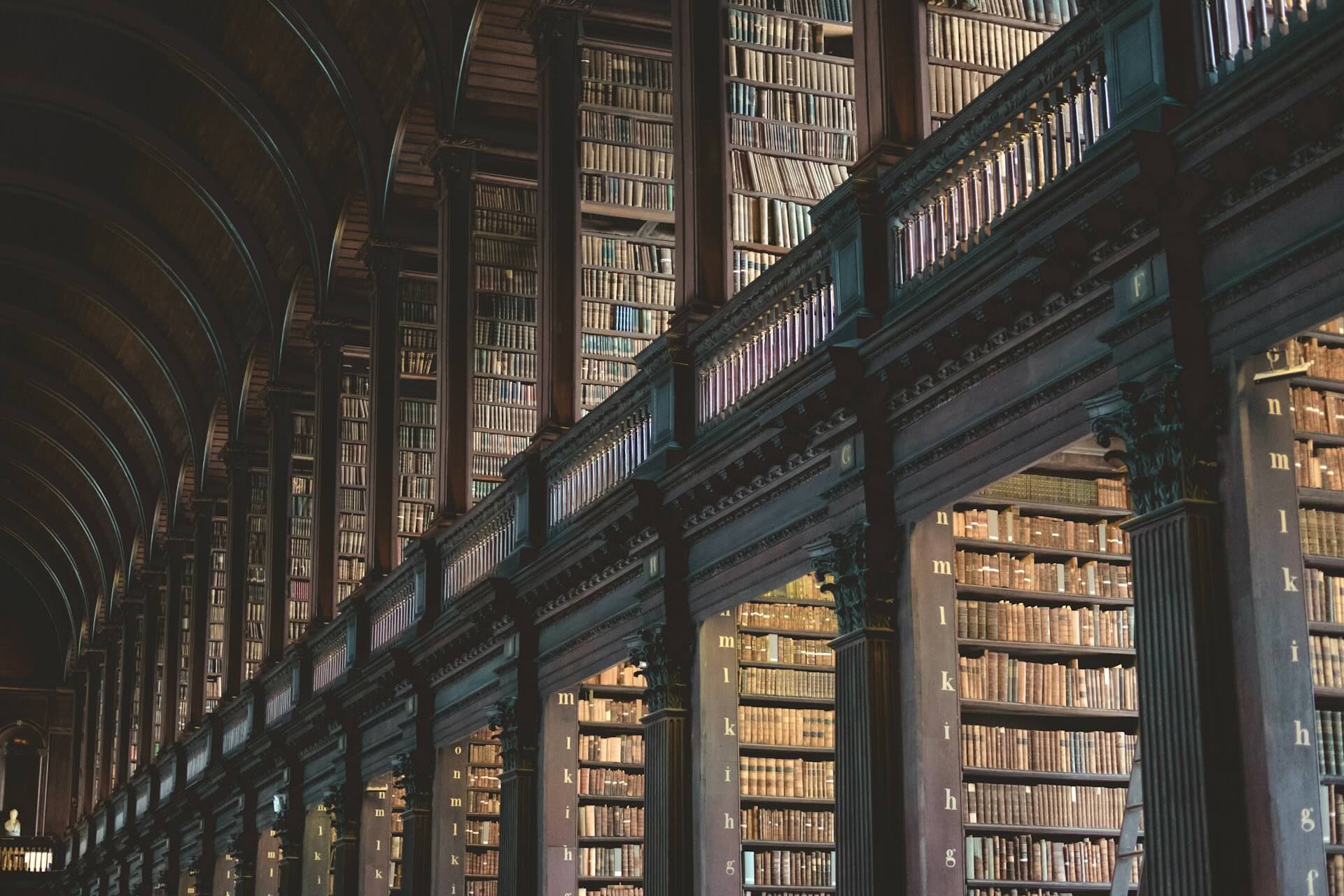 Inside main hall of a large multi-story ornate library with a sweeping arched ceiling.